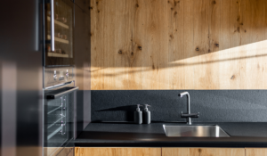Kitchen with a combination of melamine with a wood texture and black on its backsplash 